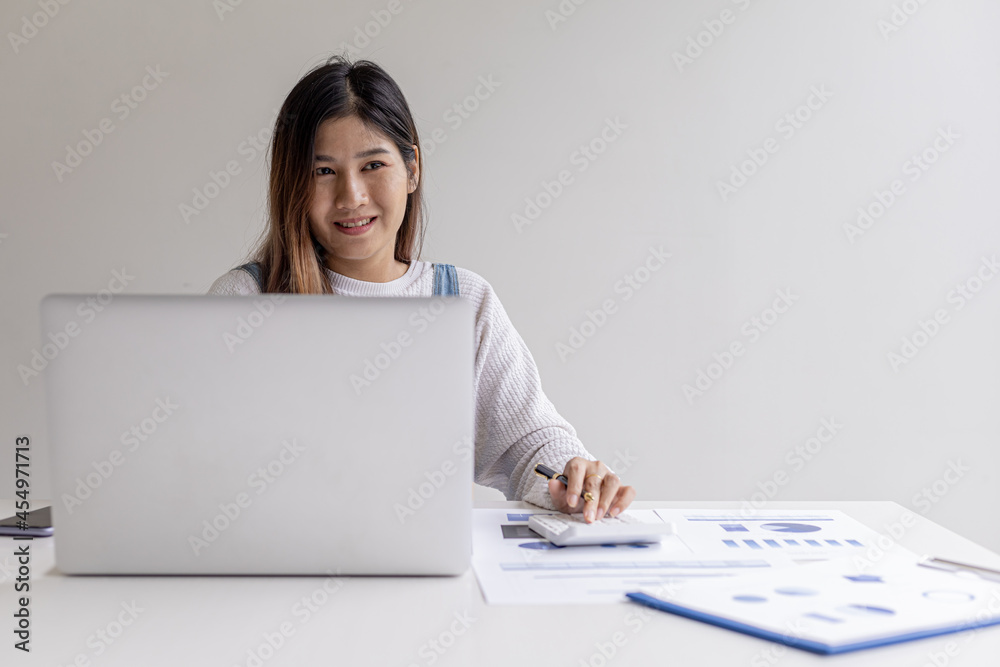 A businesswoman presses a calculator and uses a laptop, she talks to a finance manager through a laptop messaging program, managing finances to grow. Concept of financial management. A businesswoman presses a calculator and uses a laptop, she talks to a finance manager through a laptop messaging program, managing finances to grow. Concept of financial management.
