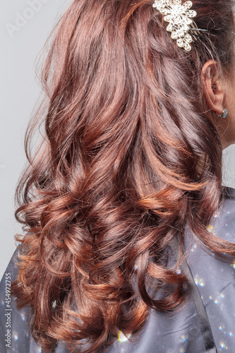 Back view of the girl's long curly hair. The hair is brown. Hairstyle. Close-up.