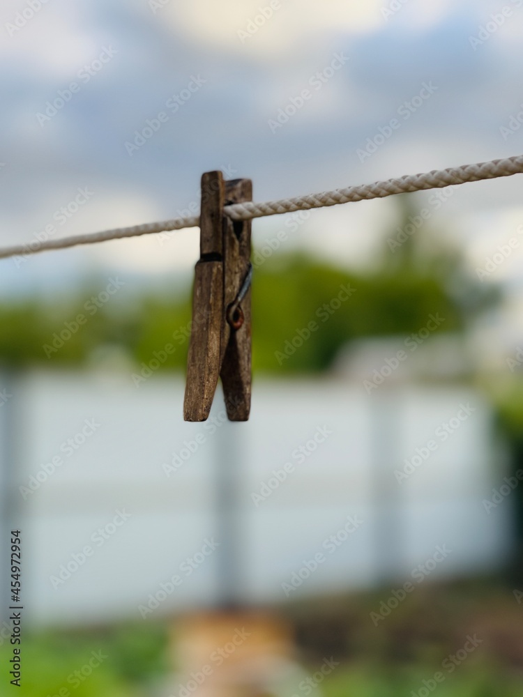 Old wooden clothespin on rope on street in countryside. Clothespin hanging on rope in yard of house. Old wooden clothespin on rope on street in countryside. Clothespin hanging on rope in yard of house.