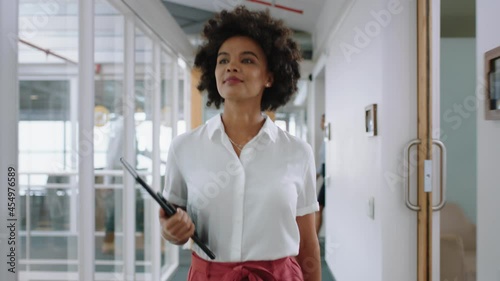 mixed race business woman smiling walking through office holding tablet computer enjoying successful career in corporate workplace 4k