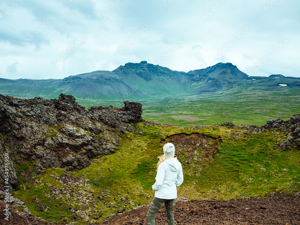 Woman in jacket stands at the edge of an inactive volcano in Iceland