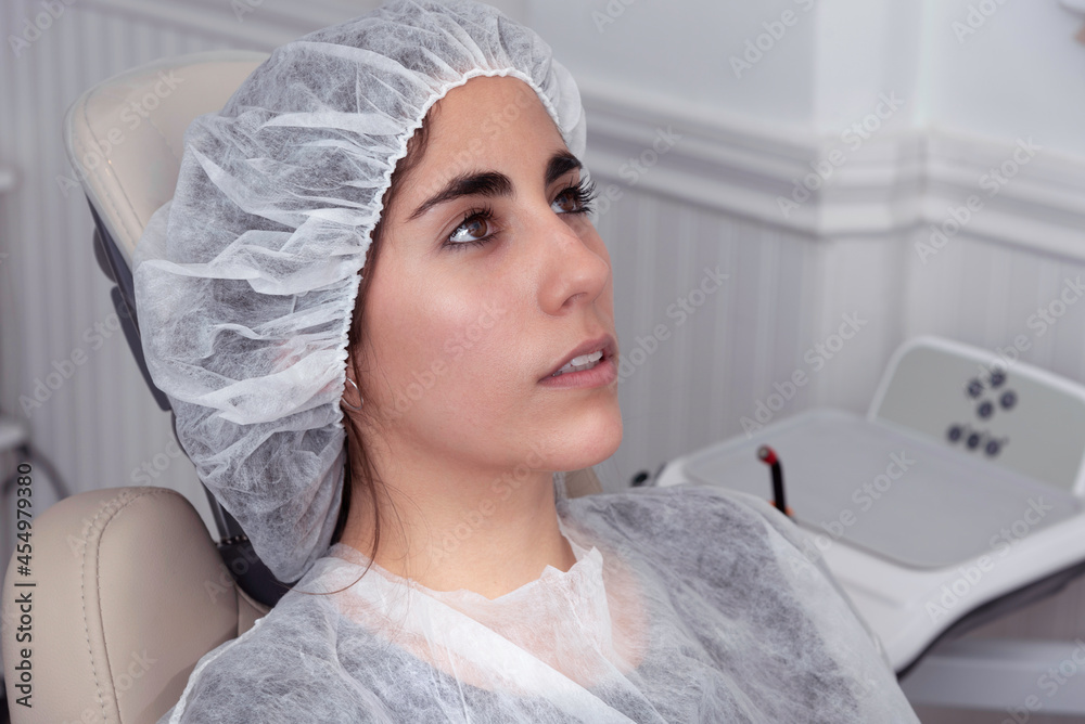joven mujer cubierta con una cofia y delantal para ser atendida por el  dentista en tiempos de covid19 Stock Photo | Adobe Stock
