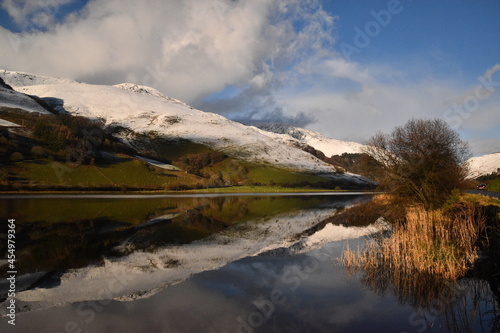 the still waters of tal-y-llyn lake with the snow covered welsh mountain tops reflected in its waters