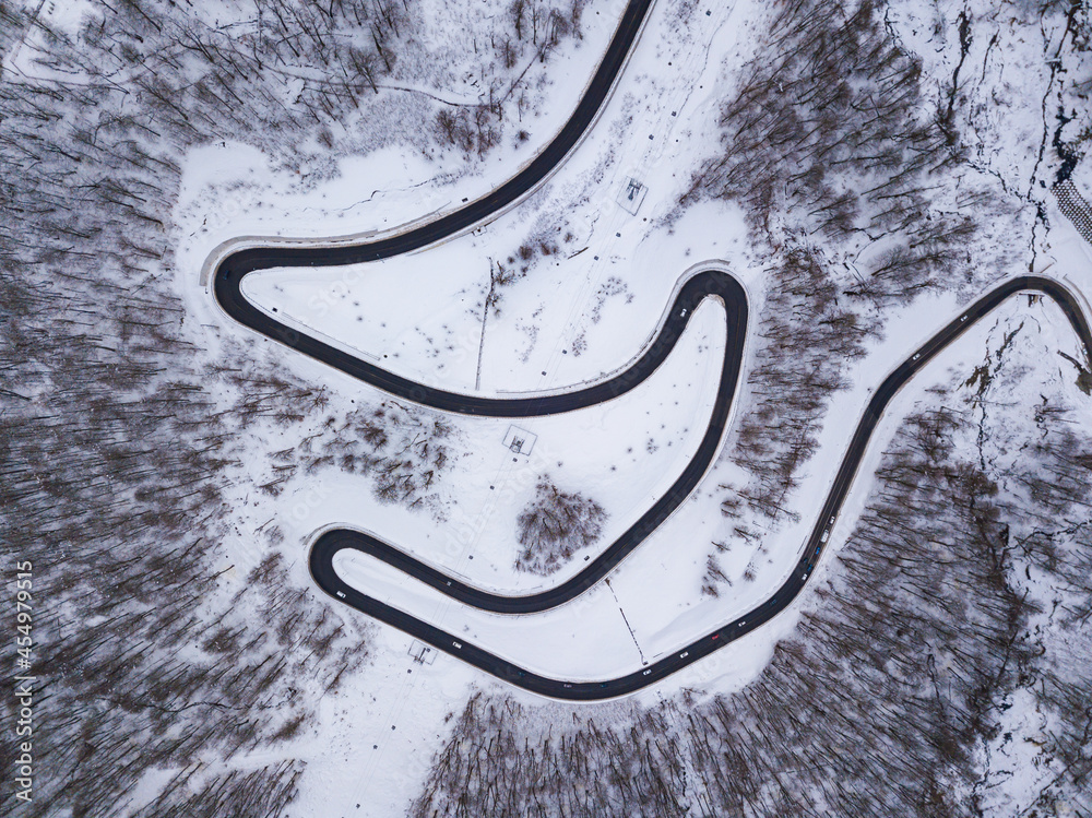 Winter aerial top view of the road to Olympic mountain village Roza Plato. Beautiful winter landscape from drone.