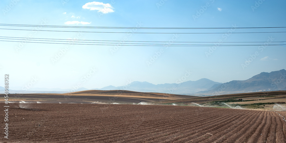 rows of soil before planting. Furrows row pattern in a plowed field prepared for planting crops in summer in iran. watering the plowed wheat field rows of soil before planting. Furrows row pattern in a plowed field prepared for planting crops in summer in iran. watering the plowed wheat field