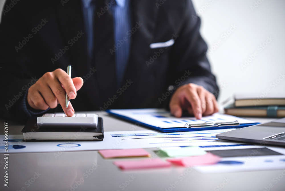 Businessman calculating on charts and graphs showing successful performance business idea Businessman calculating on charts and graphs showing successful performance business idea