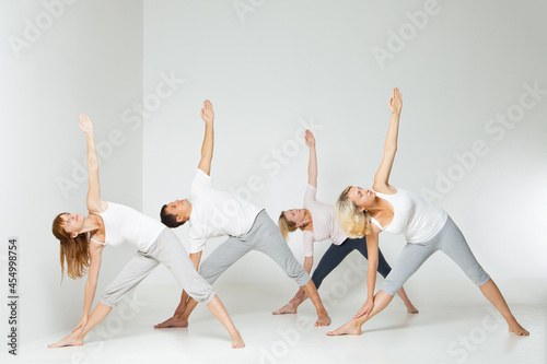 Group of people relaxing and doing yoga in white