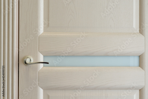 Beige curved handle on textured door with glass insert / interior