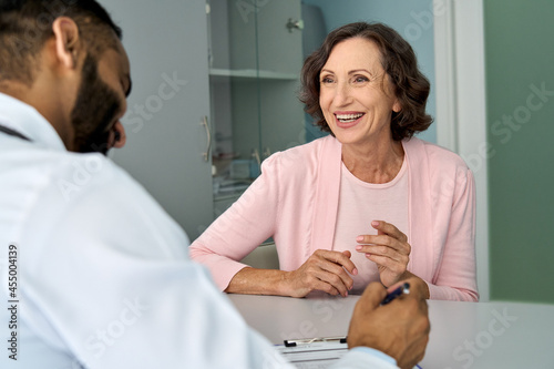 Valokuvatapetti Happy older mature female patient talking to indian male doctor at appointment