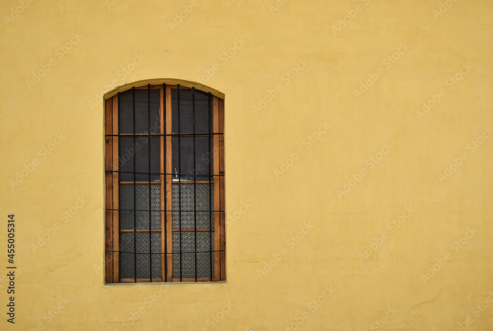 Ventana de madera en una pared amarilla, por las calles de Antigua Guatemala.