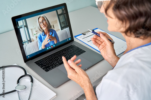 Quadro su tela Female doctor therapist consulting older senior patient via virtual video call visit using laptop computer