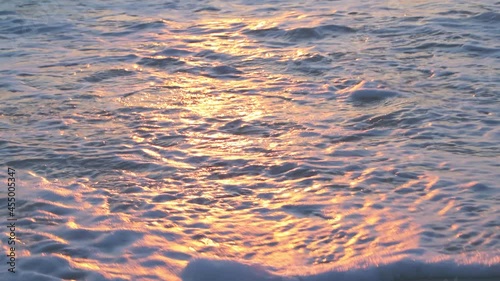 Sunset in Seaside, Santa Rosa Beach, Florida in panhandle with closeup of shore and gulf of mexico ocean waves and reflection of sun path in water surface