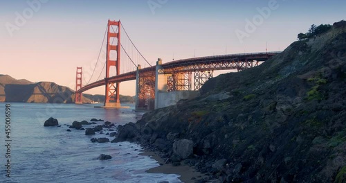 Aerial: Golden Gate Bridge and waves crashing on Marshall Beach at sunrise. San Francisco, USA