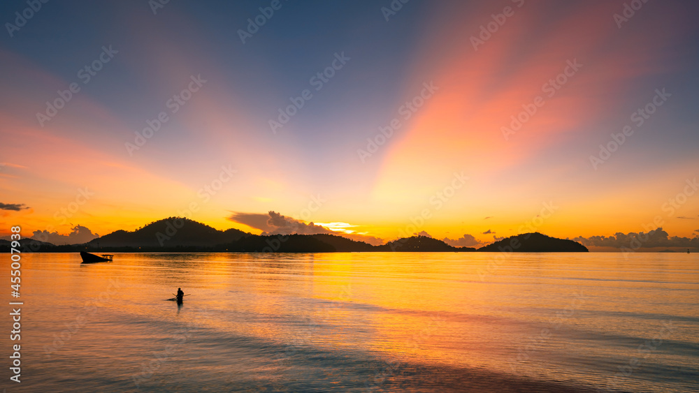 Beautiful sunset or sunrise over sea with silhouette of fisherman in the sea Mountain background at sunset long exposure photo Amazing landscape.