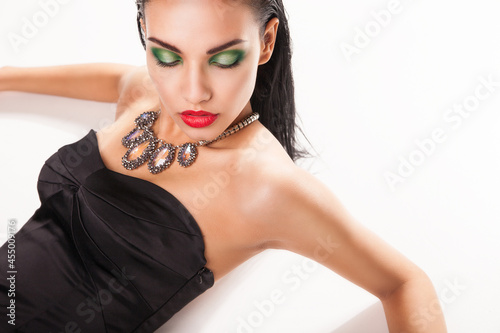 Beautiful woman in jewellery laying over white