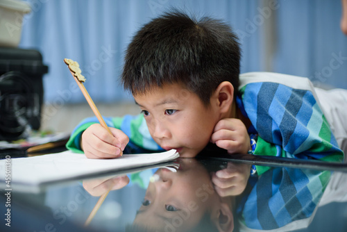 Asian boy doing homework on green screen, child writing paper,  education concept, back to school
