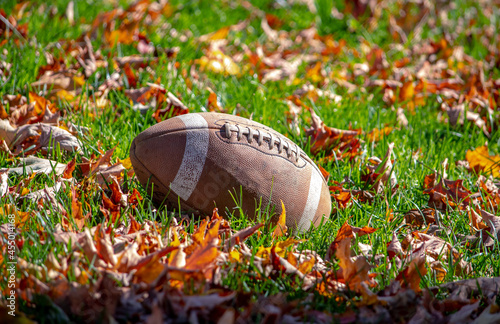 American football ilies in the leaves and grass on a fall day