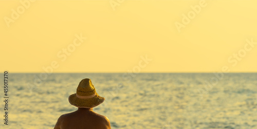 unrecognizable senior man wears straw hat sunbathing at sea beach