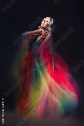 Young beautiful female model in colorful dress on black background