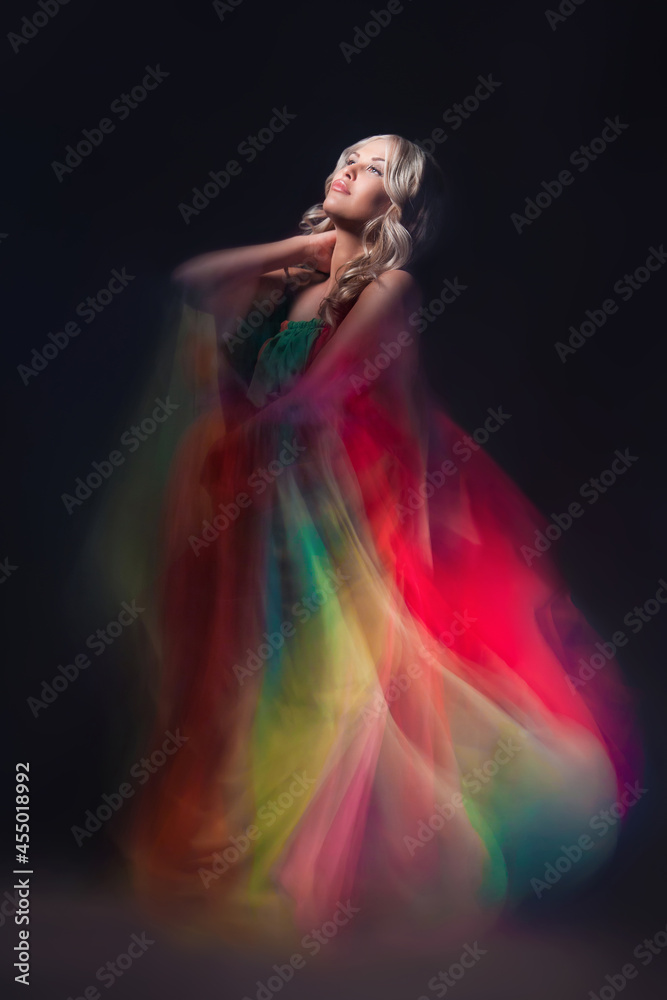 Fototapeta premium Young beautiful female model in colorful dress on black background