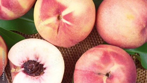 Top view Rotate Fresh peach with slices closeup, White peach on Bamboo mat on wooden table in garden.