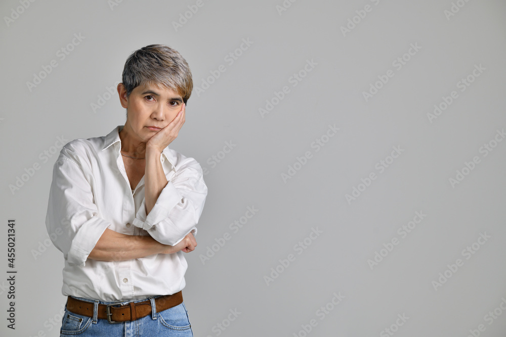 Image of confused puzzled upset middle aged Asian woman standing isolated over white background. Looking at the camera Image of confused puzzled upset middle aged Asian woman standing isolated over white background. Looking at the camera