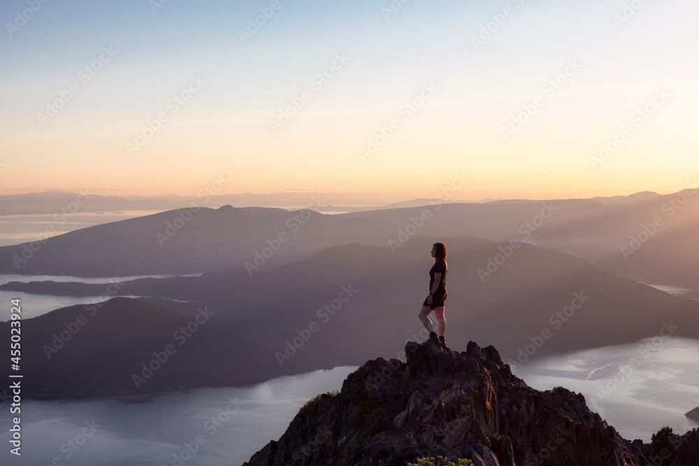 Adventurous Caucasian Woman Hiking on top of a Rocky Mountain Cliff. Sunny Summer Sunset. Mnt Brunswick Hike, North of Vancouver, British Columbia, Canada. Adventurous Caucasian Woman Hiking on top of a Rocky Mountain Cliff. Sunny Summer Sunset. Mnt Brunswick Hike, North of Vancouver, British Columbia, Canada.