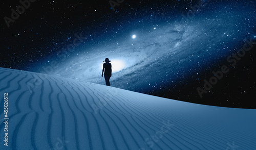 Fototapeta Naklejka Na Ścianę i Meble -  Silhouette of woman walking on the sand dune - Amazing view of the blue desert under the night starry sky with Andromeda galaxy 