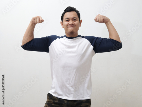 Εκτύπωση καμβά Funny Asian man shows double biceps pose pretending to be a strong person physic