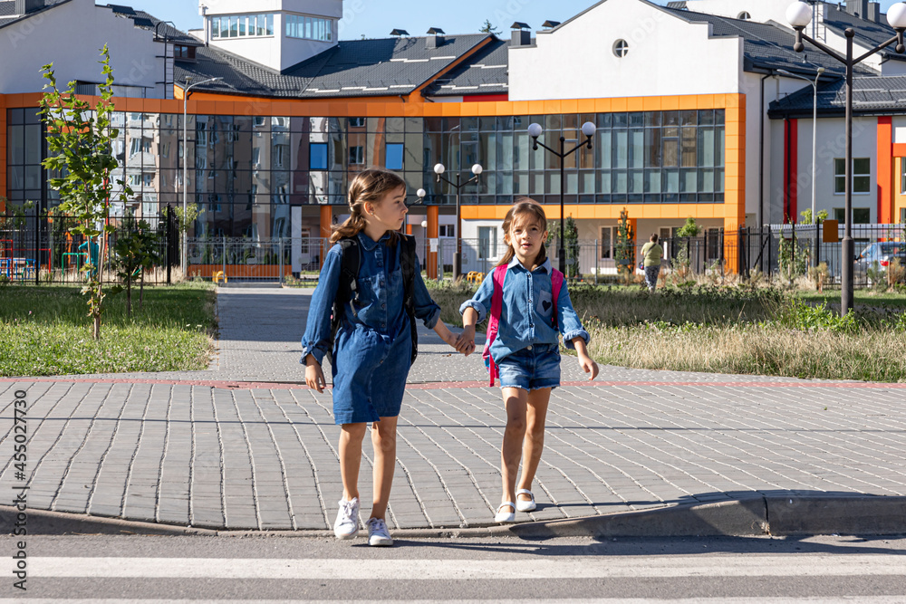 Cute little girls with backpacks go home from school. Cute little girls with backpacks go home from school.