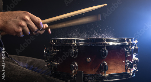 Photography A man plays with drumsticks on a snare drum with splashing water.