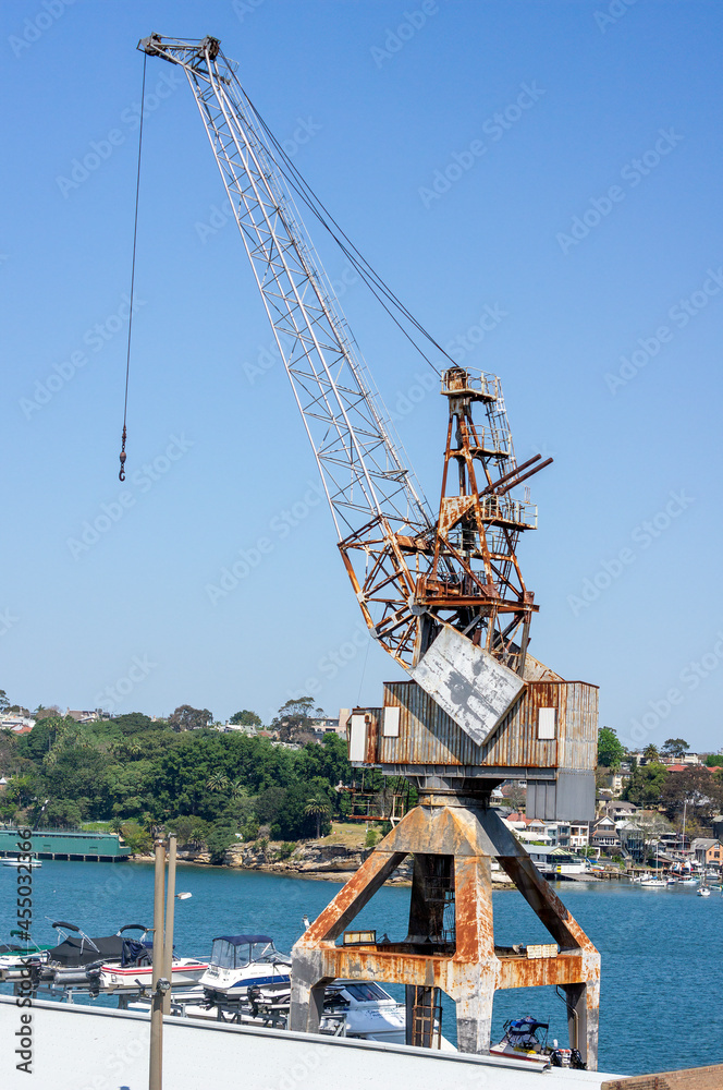 Fototapeta premium View of crane near marina on Cockatoo Island with houses in background, Sydney, NSW, Australia