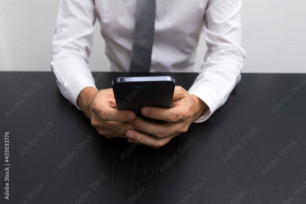 Close up of business man hands using smartphone on a black wood table. Close up of business man hands using smartphone on a black wood table.