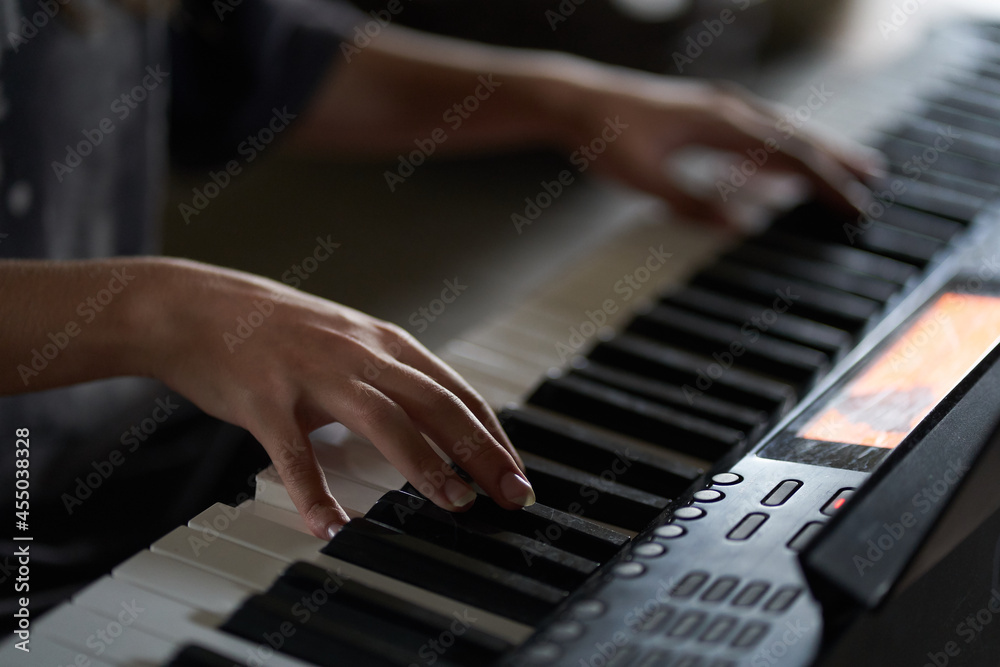 The musician's hands on the synthesizer. A cropped image of a person playing a synthesizer. Side view. High quality photo