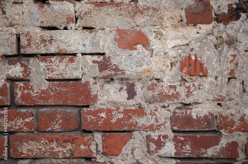 the texture of a red old brick wall with white scuffs and gray cement © Olga