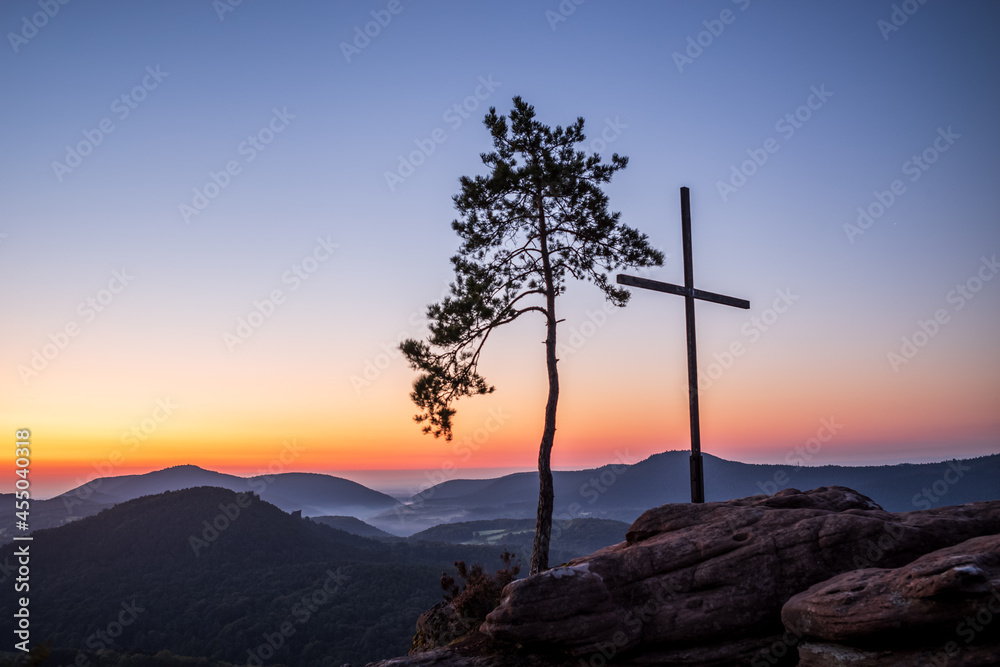 summit cross and pine tree at dawn