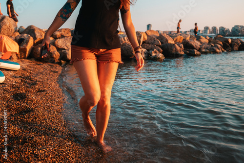A woman with a club foot steps on the seashore. Legs close-up. The concept of clubfoot and arthritis photo