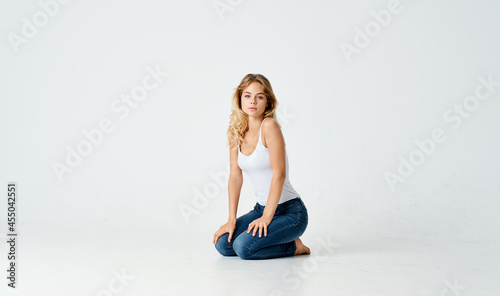 pretty blonde in jeans sitting on the floor isolated background