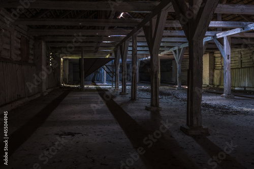 inside dark abandoned ruined wooden decaying hangar with rotting columns