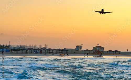 Sunset over the Mediterranean Sea sandy beach of Tel-Aviv city and landing ai...