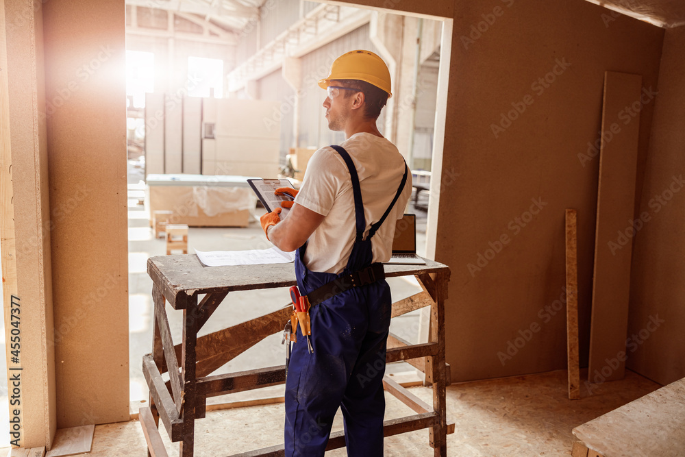 Male worker writing on clipboard at construction site