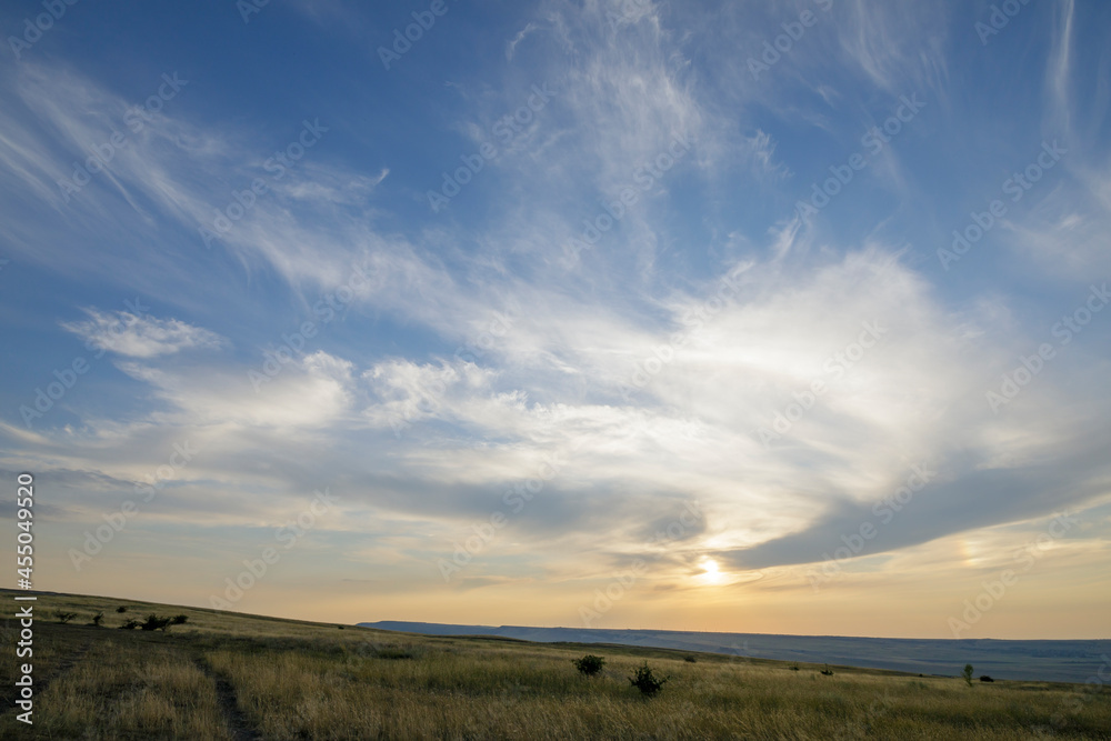 Peaks of hills with steppe grass. Sunset sky and feather clouds. Peaks of hills with steppe grass. Sunset sky and feather clouds.