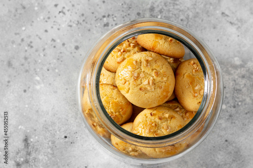 Homemade Norwegian butter cookies with almonds in a glass jar on a light gray culinary background. Traditional Scandinavian pastries top view