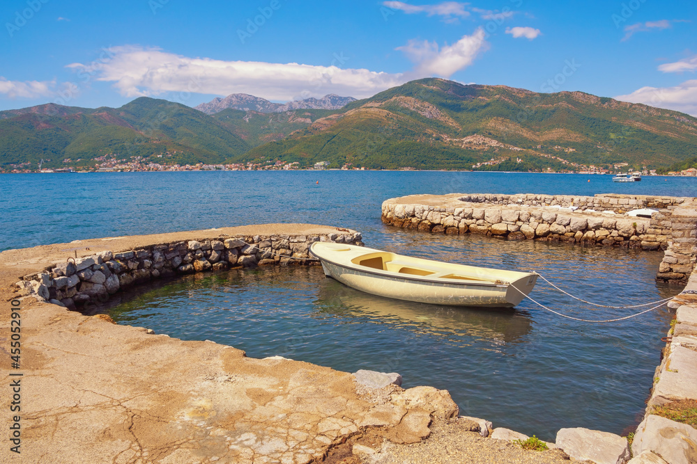 Beautiful Mediterranean landscape with fishing boat in small harbor. Montenegro, Adriatic Sea, Bay of Kotor