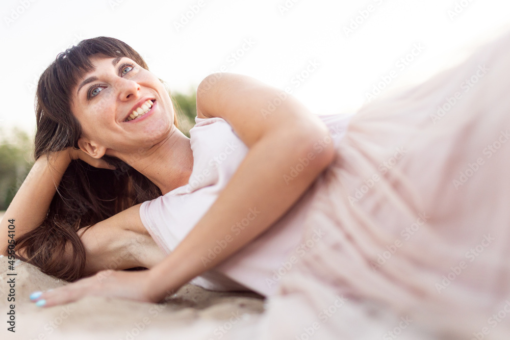 a girl in a pink dress lies on the sand a girl in a pink dress lies on the sand