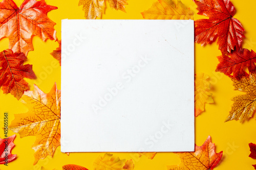Romantic mockup background with autumn leaves on yellow background