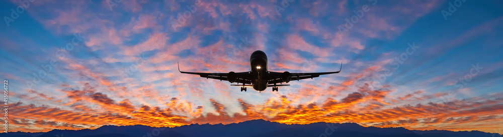 Landing airplane among beautiful clouds above mountains