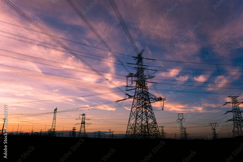 A silhouette of an electric tower against a beautiful sunset background