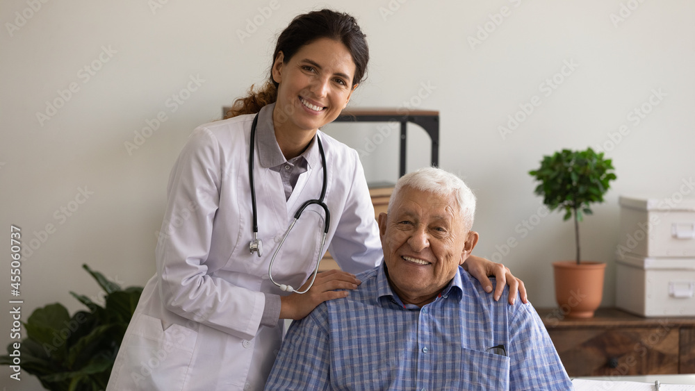 Fototapeta premium Head shot portrait of optimistic young female therapist and happy older patient. Senior man visiting doctor, looking at camera, smiling, staying healthy due to good treatment, geriatric medic care