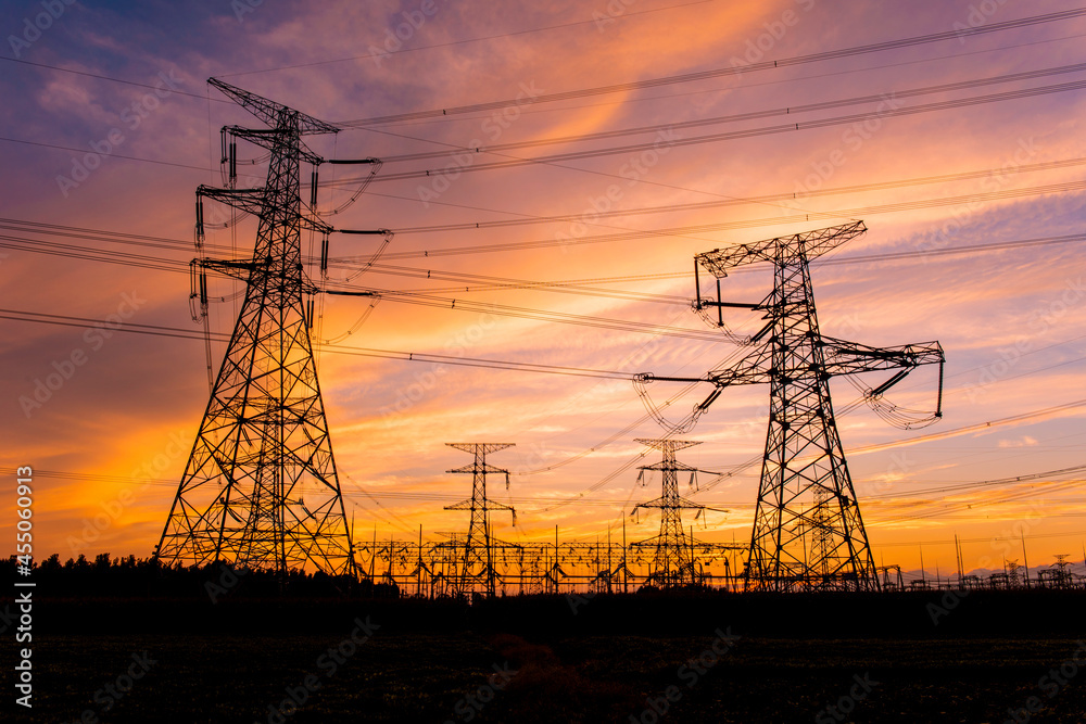 A silhouette of an electric tower against a beautiful sunset background